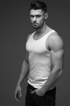 young man with a beard. A man in a t-shirt. Male portrait on a gray background. Stylish man. black and white photo. Sports man. male fitness model. studio portrait