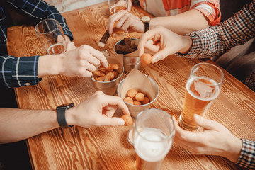 Man hand takes snacks crackers, croutons with sauce and drinks beer in pub bar at wooden table