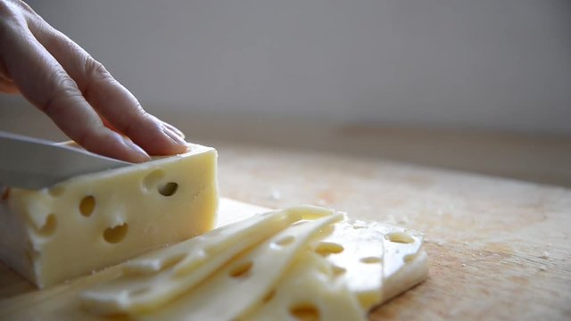 Woman cut slice cheese for cook using knife in the kitchen - people making food with cheese concept