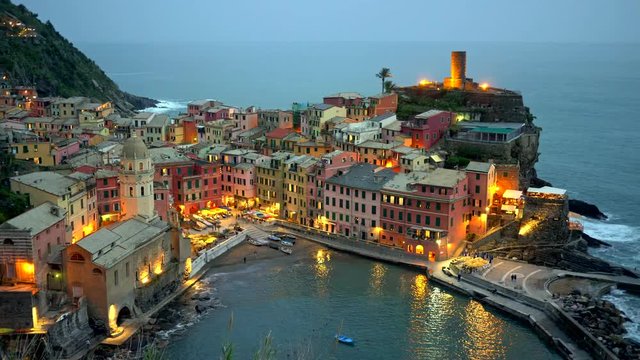 Panorama of night Vernazza, Italy. The Mediterrenean Sea washes the coast this town is located on. Lights from pastel-colored houses are reflecting in the water. Vernazza is one of 5 Cinque Terre