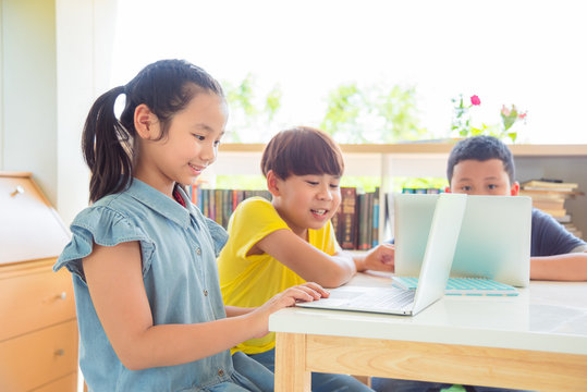 Young asian students working with notebook computer together in school library .