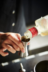 Making cocktail, pouring liquor in jigger 