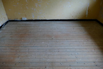 A UK Double Plug Wall Socket, Showing the Power Supply on an Unfinished Interior Wall, with Pine Floor Boards and Staining Remnants.