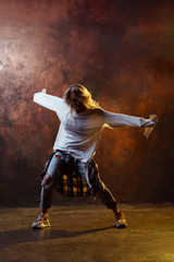 Fototapeta na wymiar Photo of dancing long-haired blonde girl in torn blue jeans on brown background