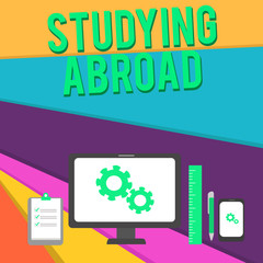 Word writing text Studying Abroad. Business concept for learn outside of home in foreign country Travelling Business Concept PC Monitor Mobile Device Clipboard Ruler Ballpoint Pen.