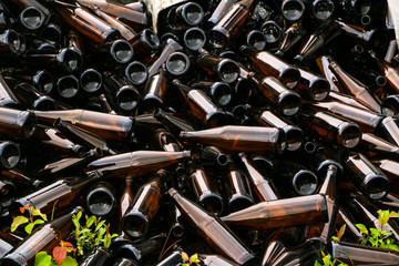 whole and broken brown bottles are scattered on gravel.Concept: waste recycling, disposal of garbage