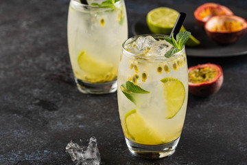 Green Lemonade drink or Mojito coctail with lime, mint, passion fruit and ice on black table.