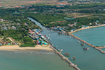 Obraz premium Aerial photo of Cha-am pier in Phetchaburi Province, Thailand shows many fishing boats parked at the port, preparing to go to catch fish in the blue sea on a sunny day