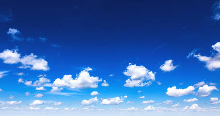 Beautiful blue sky background with sparced white clouds. Panorama. Copy space in center.
