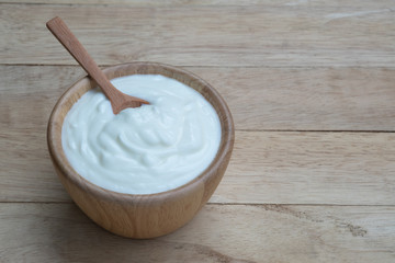 Fototapeta na wymiar Natural homemade plain organic yogurt in wooden bowl on wood texture background
