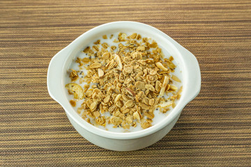 Morning food almond flakes  and milk in white bowl on wood table.