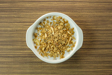 Morning food almond flakes  and milk in white bowl on wood table.