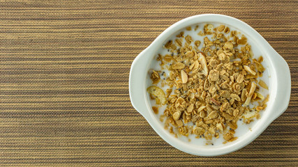 Morning food almond flakes  and milk in white bowl on wood table.