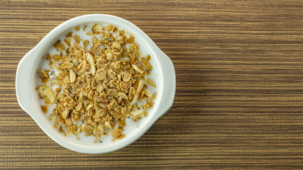 Morning food almond flakes  and milk in white bowl on wood table.