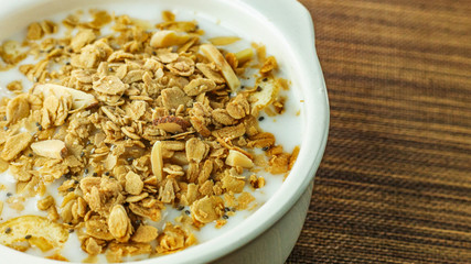 Morning food almond flakes  and milk in white bowl on wood table.