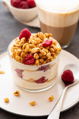 Fresh yoghurt with rasberries and coffee in clear glass. Raspberries in white bowl. Healthy morning breakfast.