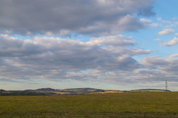 Beautiful sky with clouds over field and mountain