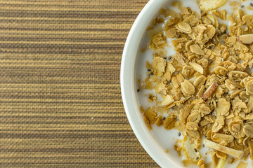 Morning food almond flakes  and milk in white bowl on wood table.