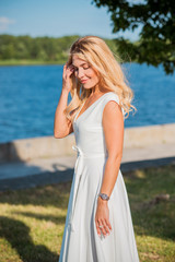 Elegant blonde hair woman in white midi dress at shore. Concept oа white code, fashionable lady, pretty dress and clothes 