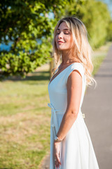 Fototapeta premium Elegant blonde hair woman in white midi dress at shore. Concept oа white code, fashionable lady, pretty dress and clothes 