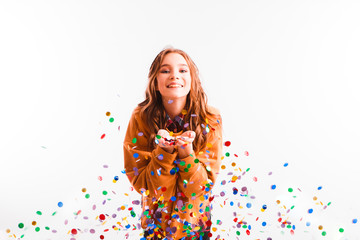 Obraz na płótnie Canvas Cute teen girl on a light background throws color candy. Party concept.