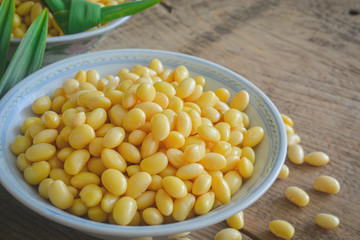 Soybean on ceramic bowl and pandan leaf on wooden table background.