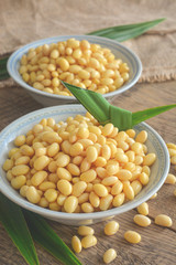 Soybean on ceramic bowl and pandan leaf on wooden table background.