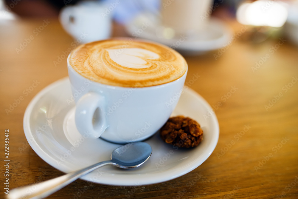 Wall mural cup with hot tasty coffee on wooden table in cafe, close up