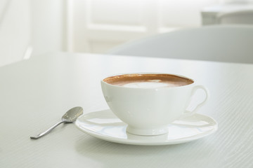 Cappuccino in a white cup on a white table