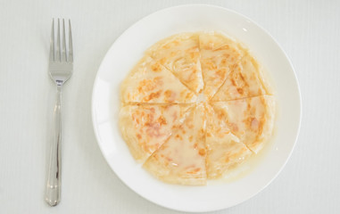 Roti with milk in a white dish and a spoon