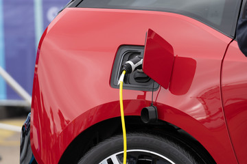 Detail of red electric vehicle being charged at station