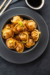 Asian dumplings in bowl, chopsticks, plates. Asian table setting. Chinese dumplings for dinner. Selective focus. Asian style decoration. Chinese fresh homemade food. Closeup