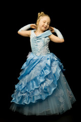 Fototapeta premium A little girl in a long, elegant dress of a princess on a black 