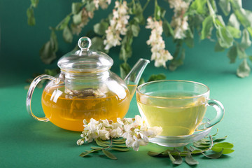Acacia tea on the background of flowers and leaves of acacia. Side view. Soft focus