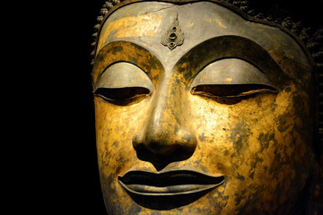 clipping path, close up of antique bronze Buddha face isolated on black background, copy space (selective focus)