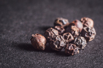 Black allspice in a pile on a dark background