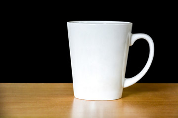 close up of white coffee or tea cup on wooden table isolated on black background, copy space, clipping path