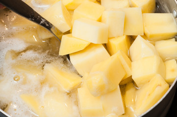 Raw potatoes in water before boiling foam in a saucepan