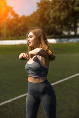 Young sportive girl with curly hairstyle on summer stadium