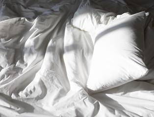 Messy bed, white bedding items top view, creative photo composition with white bed under the sun light from window