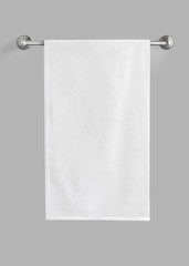 White cotton terry towel hanging on the rail isolated. White towel against the gray background.