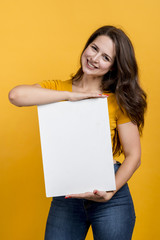Obraz na płótnie Canvas Smiling girl showing a blank poster