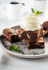 Chocolate brownie with vanilla ice cream, rasberry and mint on a white background. Copy space.