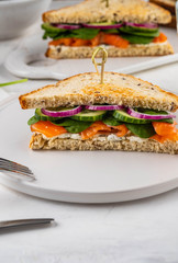 Sandwiches with cream cheese, salmon and spinach on a white backround.