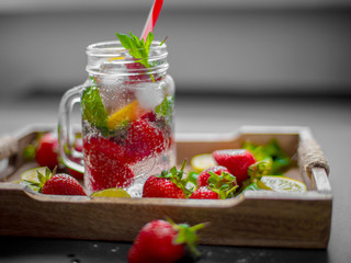 Strawberry fruit, mint leaves, lime and lemon halves on a vintage wooden tray. Mojito mix on the rustic wooden salver. Lemonade, beverage or cocktail with ice, lemon, strawberries and mint.
