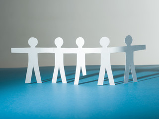 A group of paper people silhouettes stand together. One of them without legs. Symbol of social...