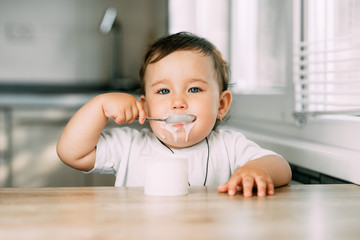 A little charming girl eats yogurt all smeared herself