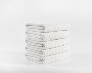 White terry towels in stack against white backdrop