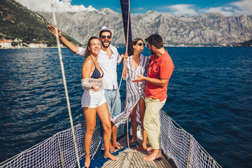 Smiling friends sailing on yacht - vacation, travel, sea, friendship and people concept