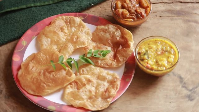 rotation Chole Bhature or Chick pea curry and Fried Puri served in terracotta crockery over wood background.